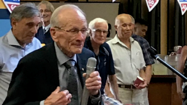Elderly man holding man and speaks at his 90th birthday