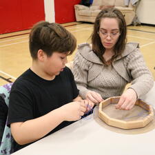 Male grade 5 student and his mother work on making a hand drum
